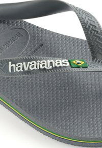 Infradito grigio in gomma con suola strutturata, caratterizzati da un logo "havaianas" bianco e un accento a strisce verde, giallo e blu.