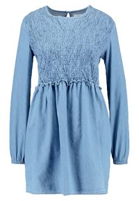 Vaaleansininen farkumekko, jossa on pitkät hihat, smockattu yläosa ja kerätty hame. Ominaisuuksiin kuuluu pyöreä pääntie ja takana nappikiinnitys.