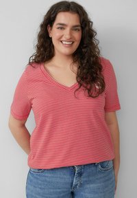 Rood-witte gestreepte t-shirt met korte mouwen en een V-hals ontwerp. Gemaakt van een zachte stof, met een relaxte pasvorm, gecombineerd met casual blauwe spijkerbroeken.