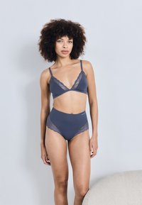 Bralette bleu marine avec dentelle, présentant un décolleté en V. Culotte taille haute assortie avec des accents en dentelle sur les côtés. Tissu doux et lisse.