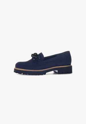 Navyblauwe suède instappers met een stevige zwarte rubberen zool, bruine gestikte weltrand en een decoratieve zwarte cord dubbelstrik bovenop.