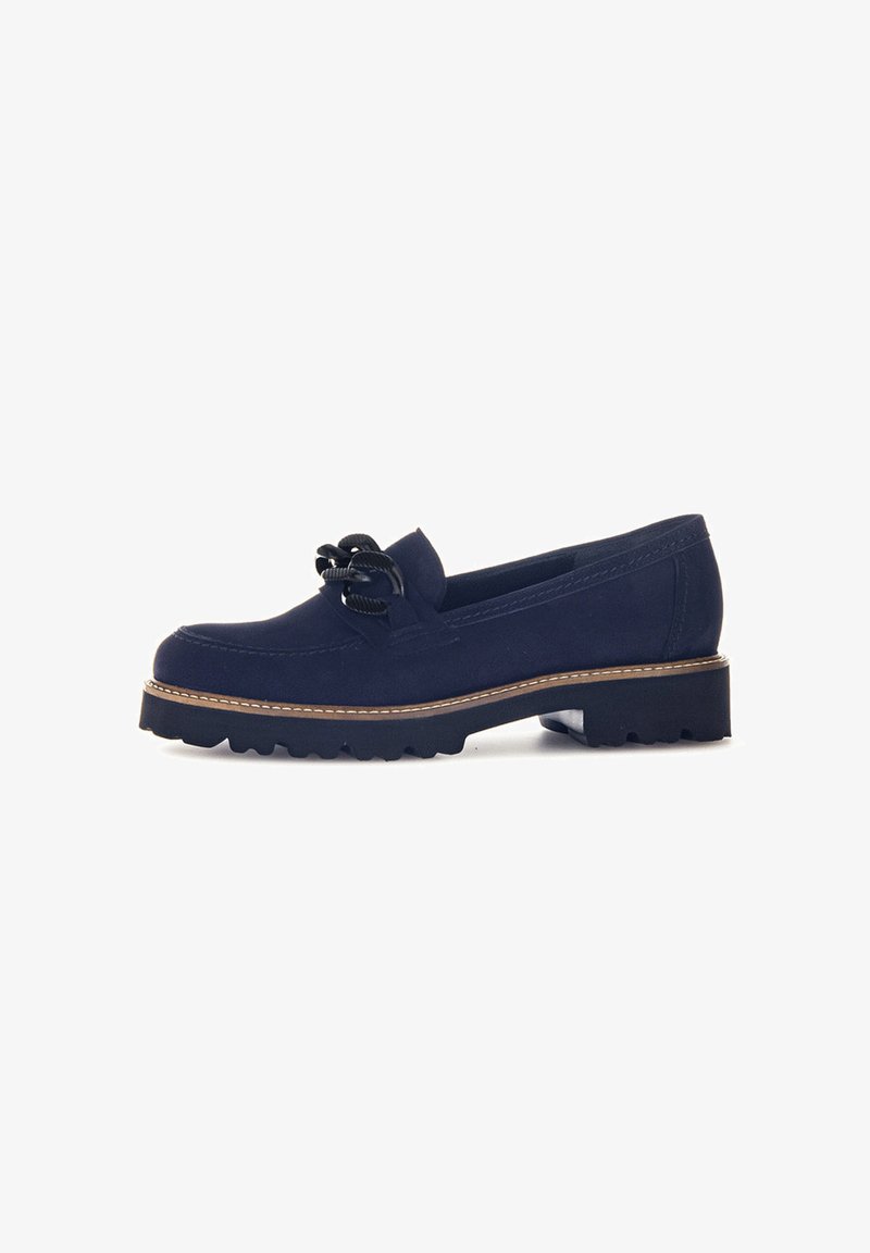 Mocassin en suède bleu marine avec une semelle en caoutchouc noir épaisse, un bord cousu marron et un nœud décoratif en cordon noir sur le dessus.