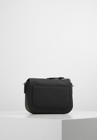 Černá kožená crossbody taška s texturovaným povrchem, obdélníkovým tvarem, přední kapsou a stříbrným kováním.