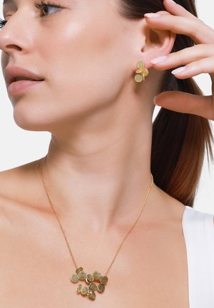 Goldfarbene Schmuckset mit Ohrsteckern und einer Halskette mit runden, strukturierten Anhängern, die am Hals und Ohr eines Modells präsentiert werden.