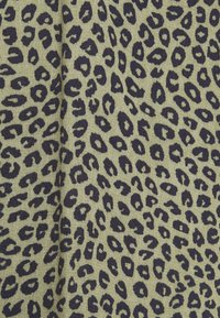 Leopardenmusterstoff mit dunkelblauen Punkten auf einem hellolivgrünen Hintergrund, der eine strukturierte, gewebte Optik zeigt.