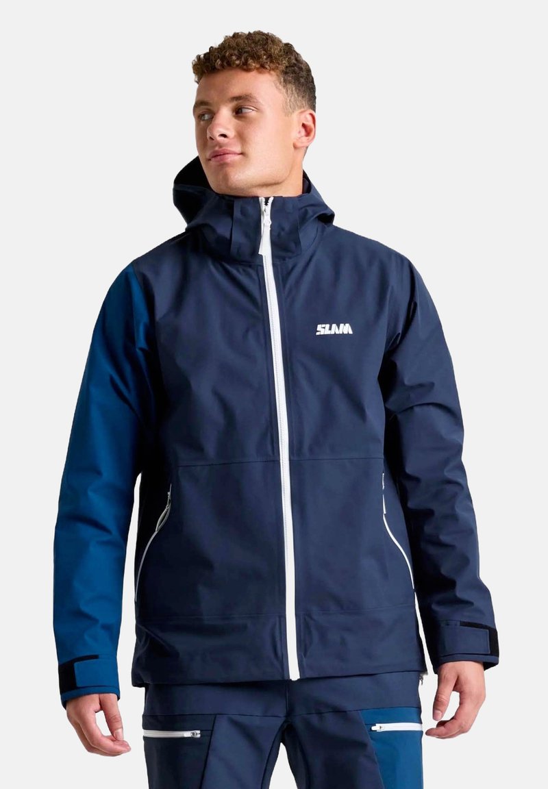 Giacca impermeabile blu navy con colletto alto, zip bianca e logo. Presenta maniche blu a contrasto e tasche con zip.