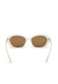 Białe okulary przeciwsłoneczne w kocim kształcie z brązowymi soczewkami, gładka plastikowa oprawa, cienkie jasne ramiona oraz złociste metalowe akcenty przy zawiasach.
