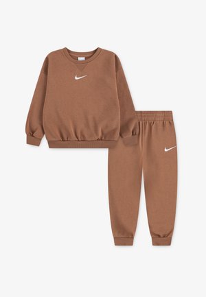 Bruine sweatshirt en bijpassende sweatpants gemaakt van zacht materiaal, met geribde boorden en een wit Nike-logo op de borst en dij.