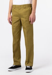 Olivgrön, raka byxor i slitstarkt material, med en klassisk midja med bälteshällor. Matchas med svarta sneakers.