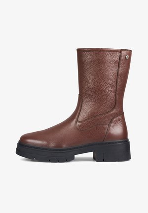 Bota de cuero marrón hasta la rodilla con superficie texturizada, suela de goma negra y detalle de costura lateral. Diseño de punta redonda y tacón cuadrado.
