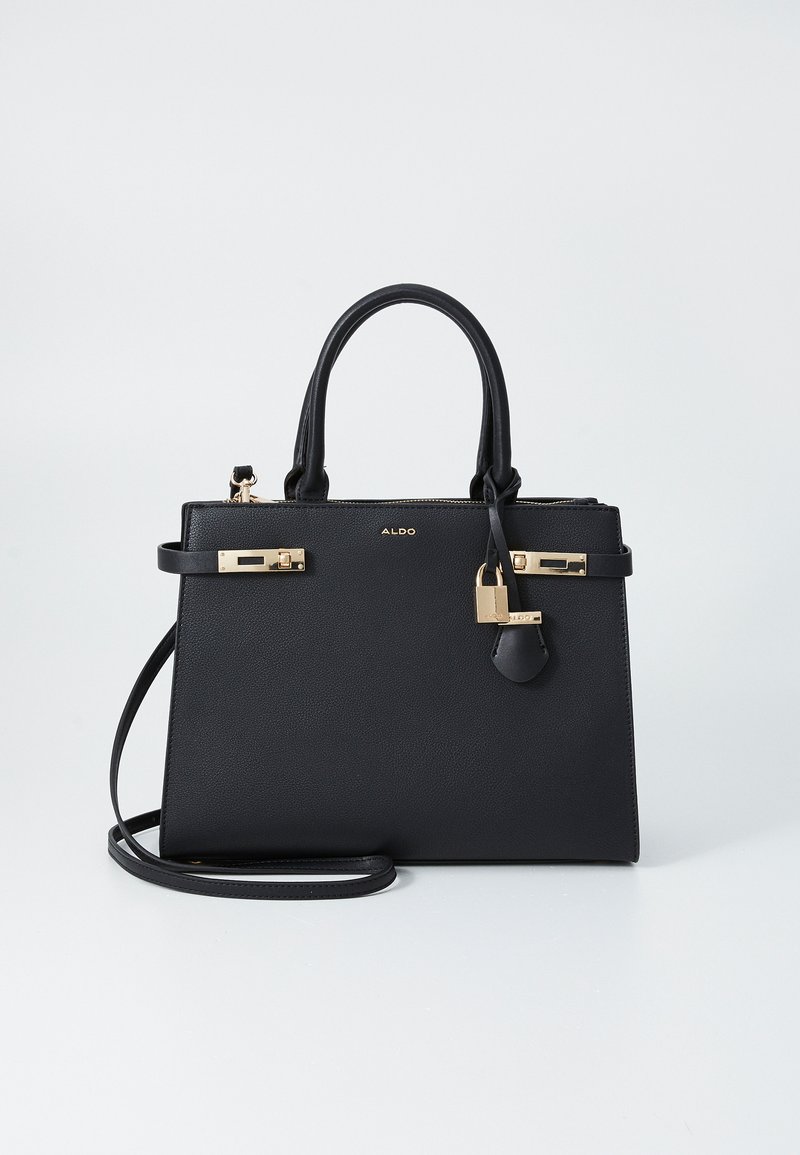 Sac à main structuré noir en matériau synthétique à texture granuleuse. Il présente des accessoires en métal doré, des poignées supérieures doubles, une bandoulière amovible et un cadenas.
