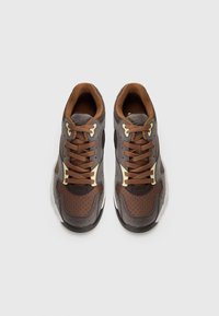 Brown and gray athletic shoes with suede and mesh upper, perforated detailing, round toe, brown laces, and contrasting cream accents.