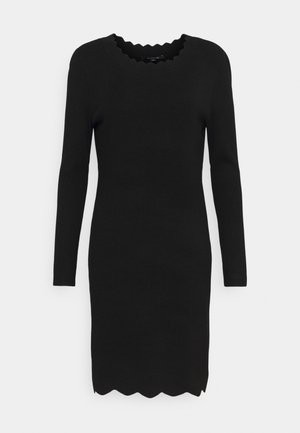 Robe noire à manches longues, longueur genou, avec des bords festonnés à l’encolure et à l’ourlet, présentée sur un fond blanc uni.