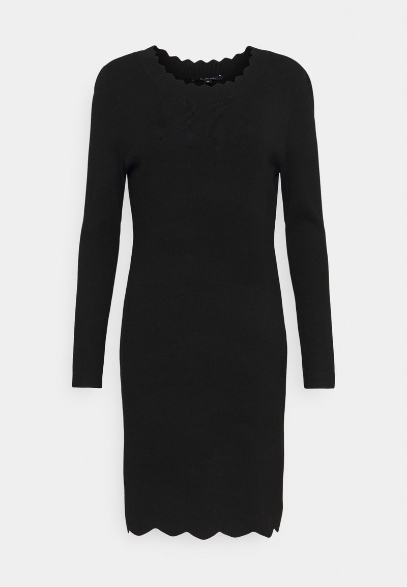 Robe noire à manches longues, longueur genou, avec des bords festonnés à l’encolure et à l’ourlet, présentée sur un fond blanc uni.