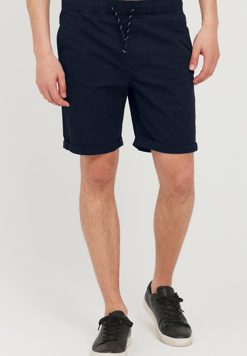 Mørkeblå shorts laget av bomull med elastisk midjebånd og justerbar snor. Har oppbrettede ermer og sidelommer.