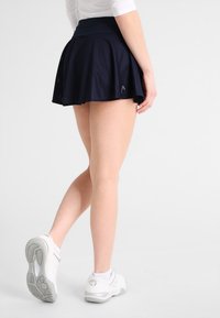 Skort azul marino ligero con diseño acampanado y textura de malla; cuenta con una cinturilla ancha y un detalle de logo en el frente.