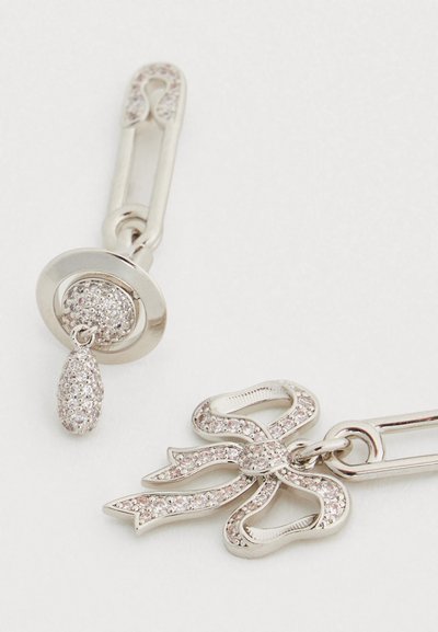 Κοσμήματα σε ασημί απόχρωση με σχέδιο ασφαλιστικού πείρου και διακοσμητικό φιόγκο, στολισμένα με μικρές διάφανες πέτρες για μια υφασμένη εμφάνιση.