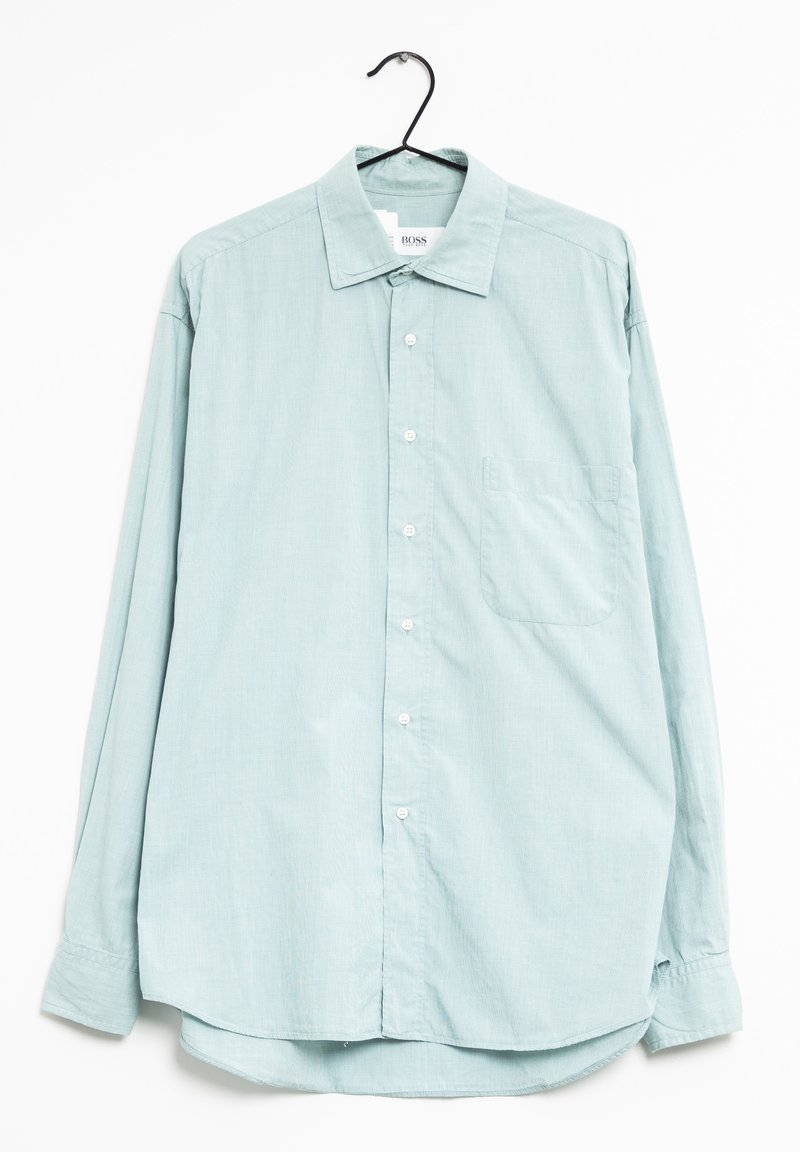 Ljusblå långärmad skjorta med knappkrage, diskret rutig mönster, en bröstficka och en rundad fåll.
