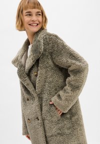 Faux fur dubbele breasted jas in olijfgroen met een brede kraag, grote knopen en zijzakken; zacht, gestructureerd materiaal.