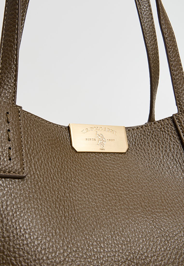 Braune, strukturierte Lederhandtasche mit zwei Schulterriemen und einem goldfarbenen Metallschild mit Logo-Detail.