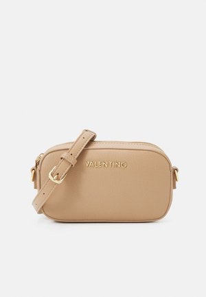 Beige kožená crossbody taška se zlatými kovovými doplňky, zipovým uzávěrem a nastavitelným popruhem. Na přední straně je vyražený název značky.