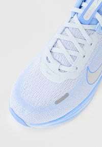 Zapatilla de running Nike en azul claro y blanco con parte superior de malla, cierre con cordones y etiqueta "Stellar Ride" en la lengüeta.