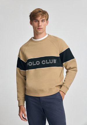 Felpa beige con una banda orizzontale nera etichettata "POLO CLUB" in bianco. Presenta maniche raglan e un materiale a trama di cotone misto.
