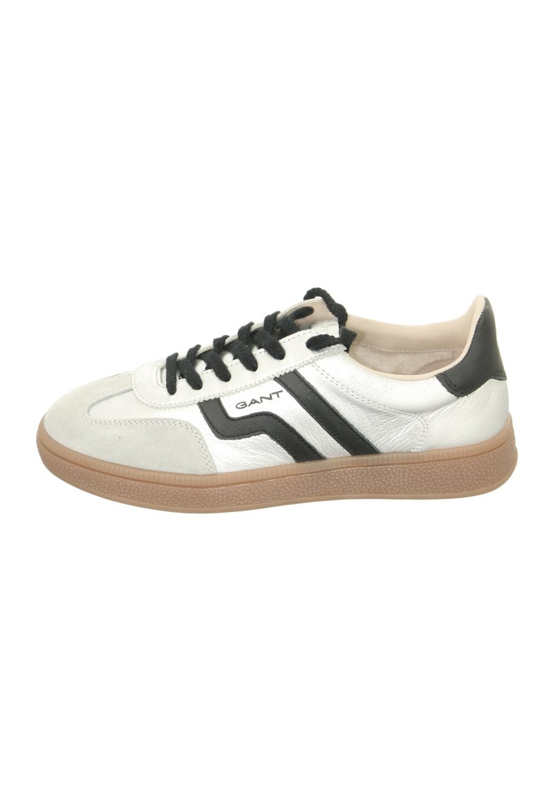 Zapatilla blanca y negra con suela de goma, hecha de materiales de ante y cuero, con cordones negros y un detalle de logo en el lateral.