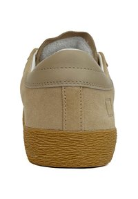 Sneaker in suede color sabbia con tallone in pelle liscia, suola in gomma e dettagli testurizzati. Presenta un colletto imbottito e un logo discreto di lato.