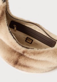 Beige bont handtas met een rits, voorzien van een bruine binnenvoering waarop de merknaam is gegraveerd. Inclusief een klein binnenvakje.