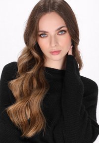 Pull en maille noir avec un motif texturé, doté de manches longues et d'un large décolleté, porté par un mannequin avec de longs cheveux ondulés.