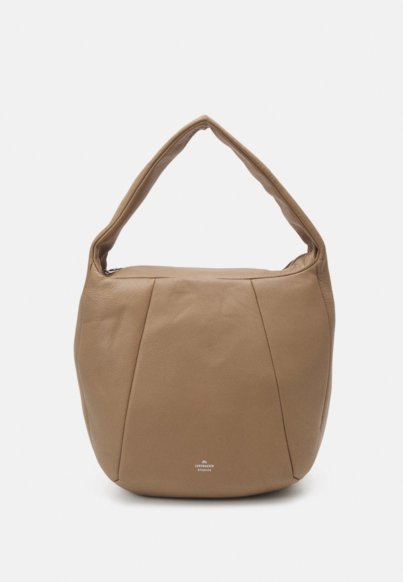 Sac à bandoulière en cuir souple et camel avec une poignée courbée et des coutures minimales, arborant un petit logo "Copenhagen Studios" à la base.