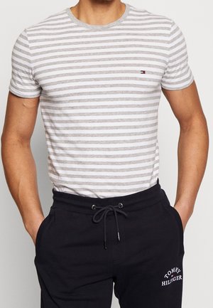 Randig t-shirt i grå och vit bomull med rundad halsringning. Har korta ärmar och en liten logotyp på bröstet. Matchas med mörka joggers.
