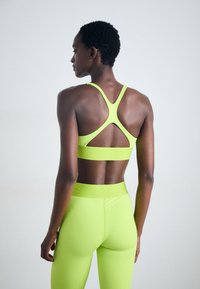 Neongrön sportbh med en korsad ryggdesign och matchande högmidjade tights, tillverkade av ett slätt, stretchigt material.
