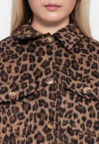 Giacca in tessuto morbido con stampa leopardata, dotata di colletto, chiusura con bottoni e due tasche sul petto con bottoni rotondi.