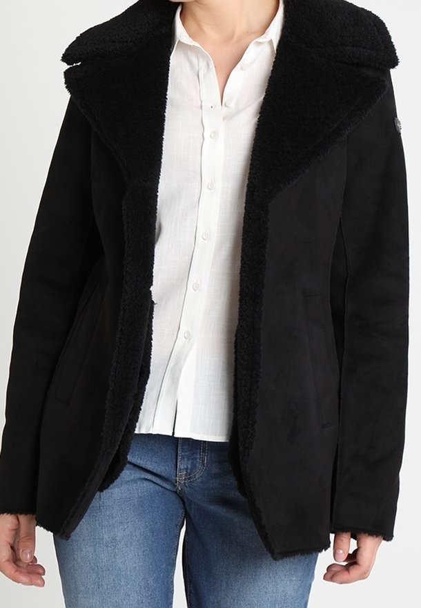 Czarna marynarka z imitacji zamszu z dużym, miękkim, czarnym kołnierzem z baranka. Posiada dwie przednie kieszenie i taliowany krój. Nosi się ją na białą koszulę.