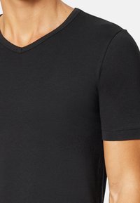 Black V-neck T-shirt made of smooth cotton fabric. Short sleeves and subtle stitching detail along the neckline and cuffs.