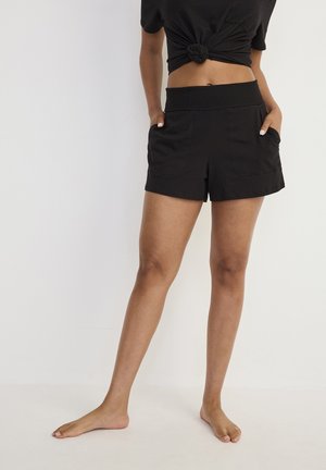 Schwarze Shorts aus weichem Stoff mit einem dehnbaren Bund, ausgestattet mit zwei Vordertaschen und einem schlichten Schnitt für optimale Bewegungsfreiheit.