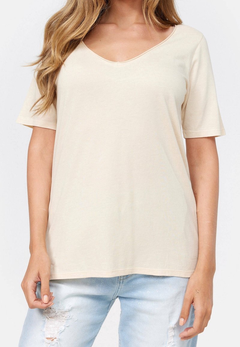 Bežové tričko s výstřihem do V vyrobené z měkké bavlny, s krátkými rukávy a volným střihem. Texturovaná látka bez viditelných vzorů nebo akcentů.
