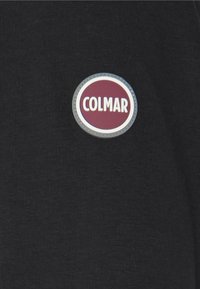 Svart tygtröja med rund, mörkröd och vit Colmar-logotyp på vänster bröstficka. Texturen verkar slät och mjuk.