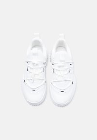 Λευκά αθλητικά παπούτσια με λείο συνθετικό επάνω μέρος, ελαστικά κορδόνια, επενδεδυμένο γιακά και υφασμένο καουτσούκ σόλα· περιλαμβάνει διακριτικές μαύρες λεπτομέρειες.