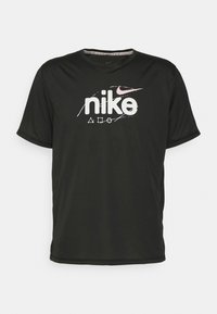 Black short-sleeve Nike t-shirt with a crew neck, featuring a white logo with pink accents and subtle graphic elements on the fabric.