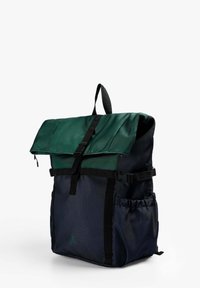 Mochila multipocket con una solapa verde, cuerpo azul marino, correas negras y un bolsillo lateral de malla. Cuenta con una hebilla ajustable y una tela texturizada.