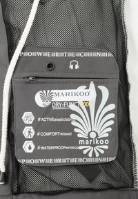 Poche en tissu gris arborant des logos et symboles liés aux caractéristiques d'étanchéité, d'élasticité et de confort ; texture en maille en arrière-plan.