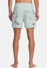 Light blue swim shorts feature floral embroidery on the sides and a back pocket with a snap closure. Made of a smooth, lightweight material.