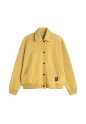Gelbe Button-up-Jacke mit Kragen, langen Ärmeln, seitlichen Taschen, gerippten Bündchen und Saum sowie einem kleinen schwarzen quadratischen Logopatch nahe dem unteren Saum.