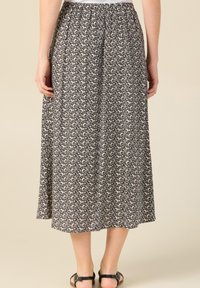 Jupe maxi à motifs noir et crème avec une taille élastique et une coupe ample. Le matériau semble léger avec un drapé et une texture subtils.