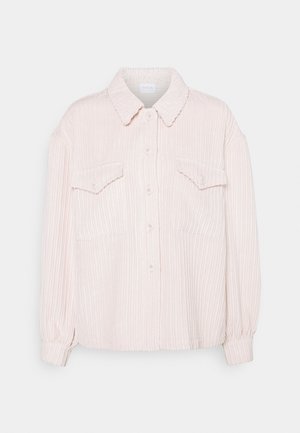Camisa de pana rosa claro con mangas largas, botones en la parte delantera, dos bolsillos con solapa en el pecho y un cuello clásico.