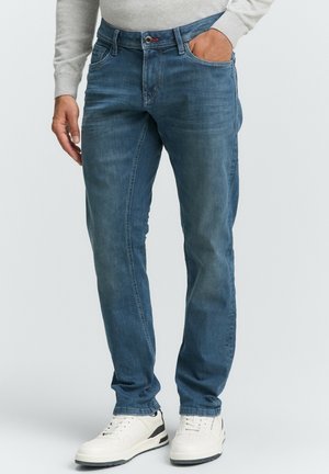 Blauwe denim jeans met een lichte vervaging, rechte pasvorm, vijf zakken en een knoopsluiting, gecombineerd met witte sneakers.