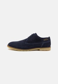 Pantofi din suede albastru închis, cu o textură netedă, design cu șnur și talpă din cauciuc deschis; prezintă detalii cusute în jurul părții superioare.